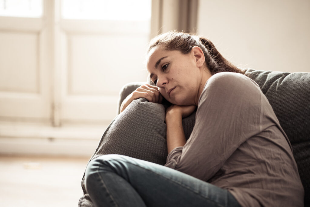 young woman with head on couch looking sad