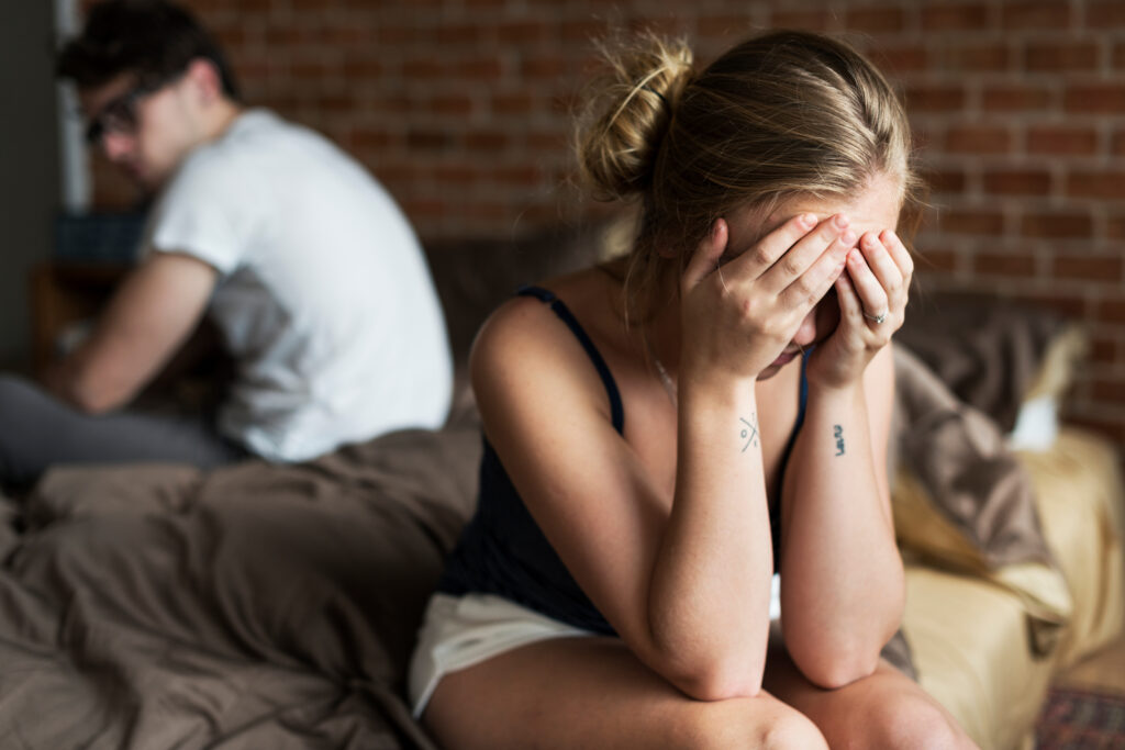 Upset couple on bed after revealing infidelity in marriage