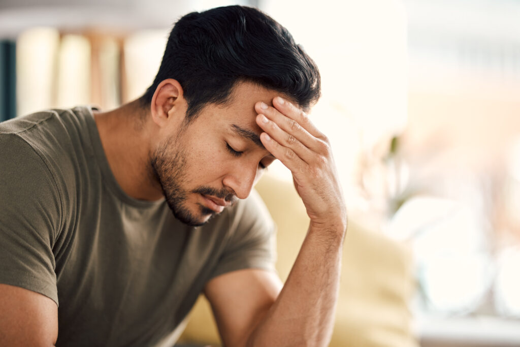 Young man with hand on forehead looking overwhelmed